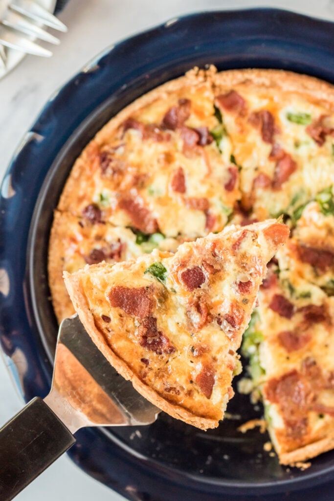 Asparagus Bacon Quiche with a piece being taken from pan