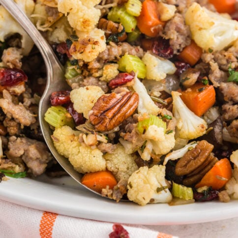 Savory cauliflower stuffing on a platter with a serving spoon