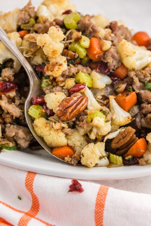 Savory cauliflower stuffing on a platter with a serving spoon