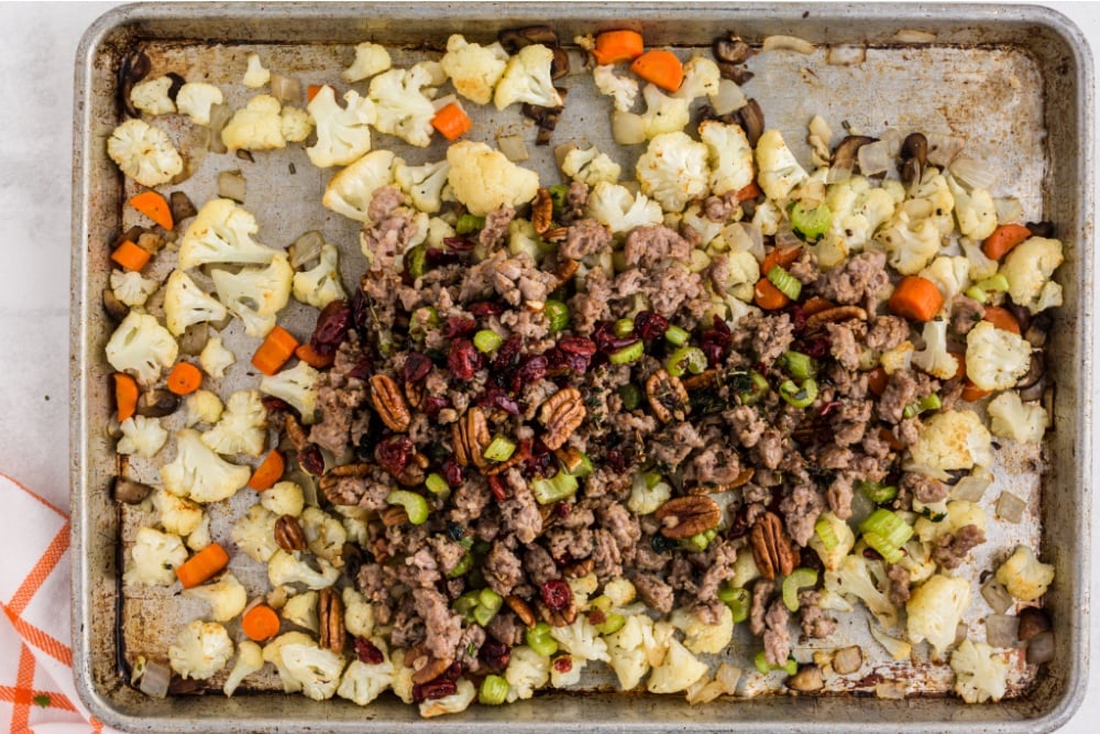 pork, cranberries, nuts, celery and herbs being added to the baking sheet