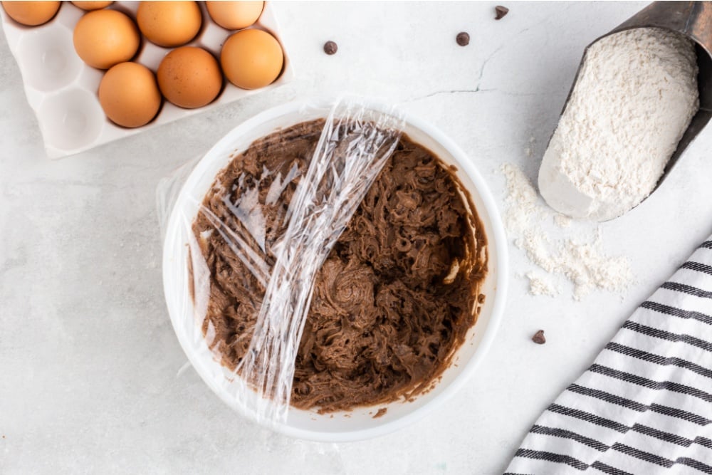 covering bowl of cookie dough with plastic wrap