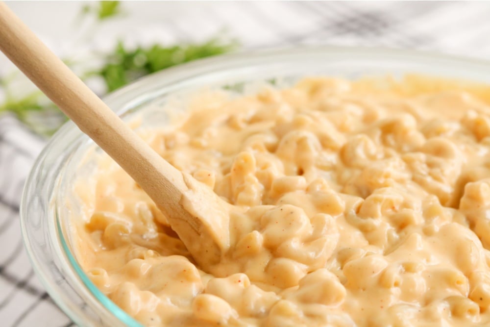 mixing together mac and cheese in glass mixing bowl