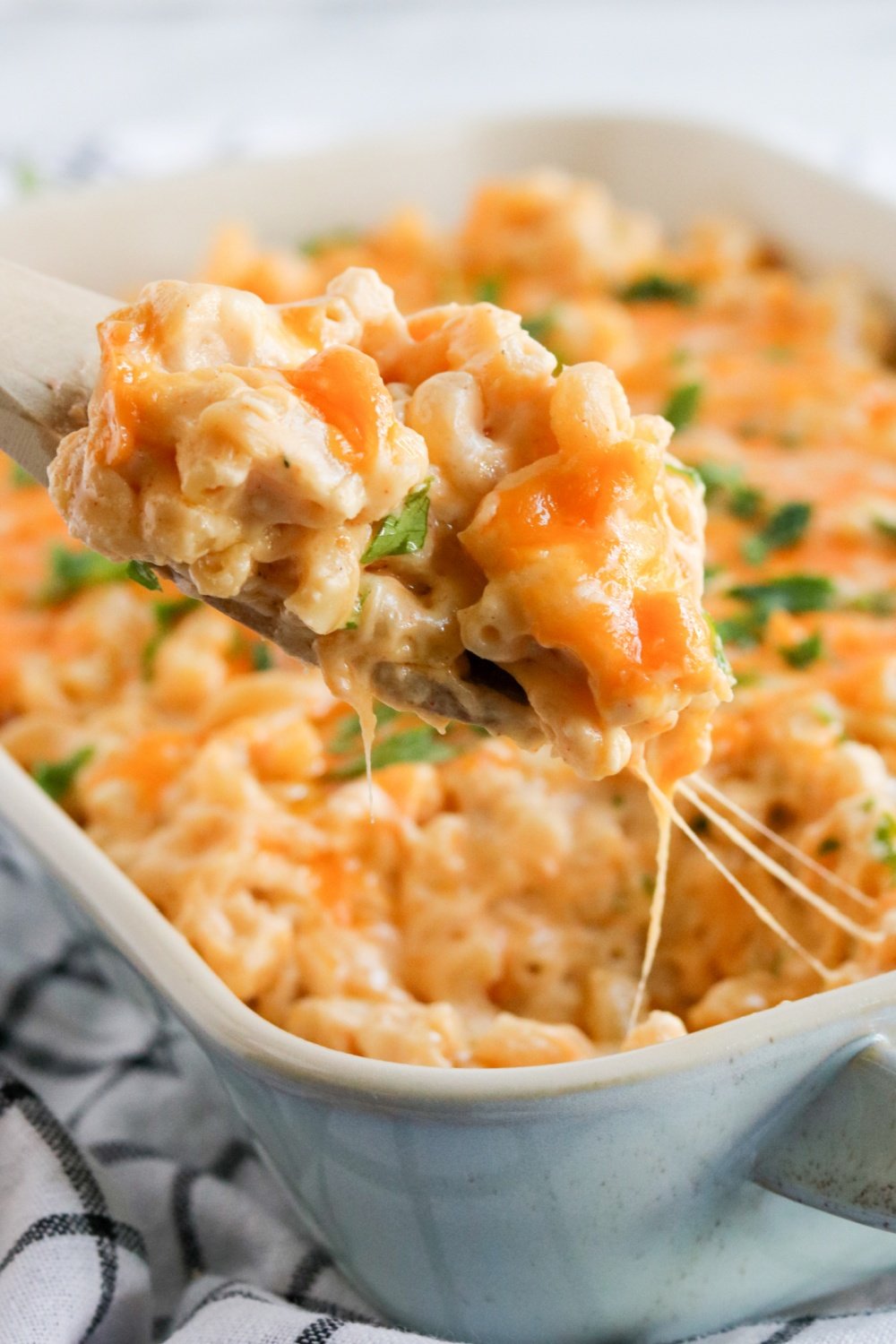 Spoon scooping out some mac and cheese from a baking dish