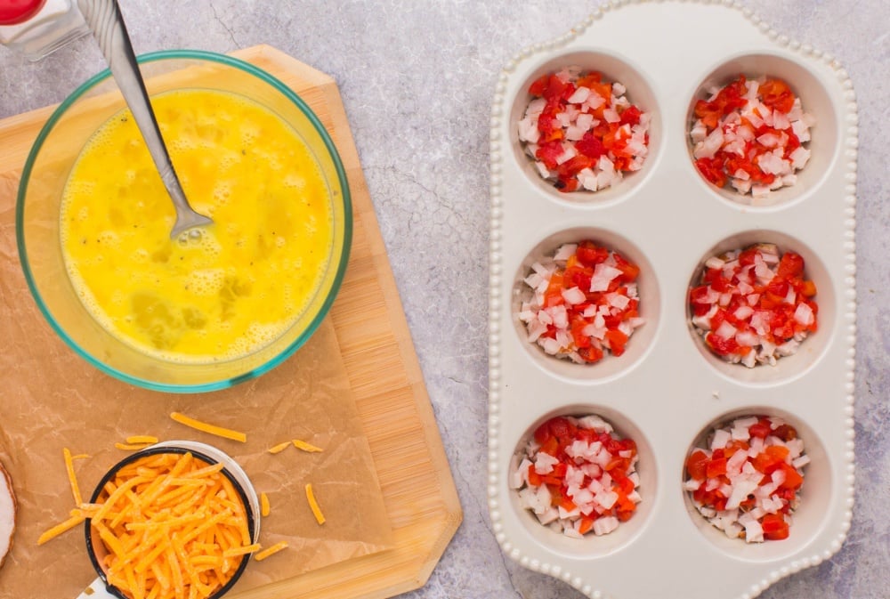 adding chopped onion and peppers into muffin tin