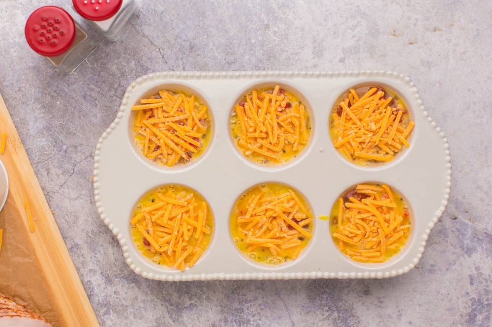 eggs and shredded cheese added to muffin tin