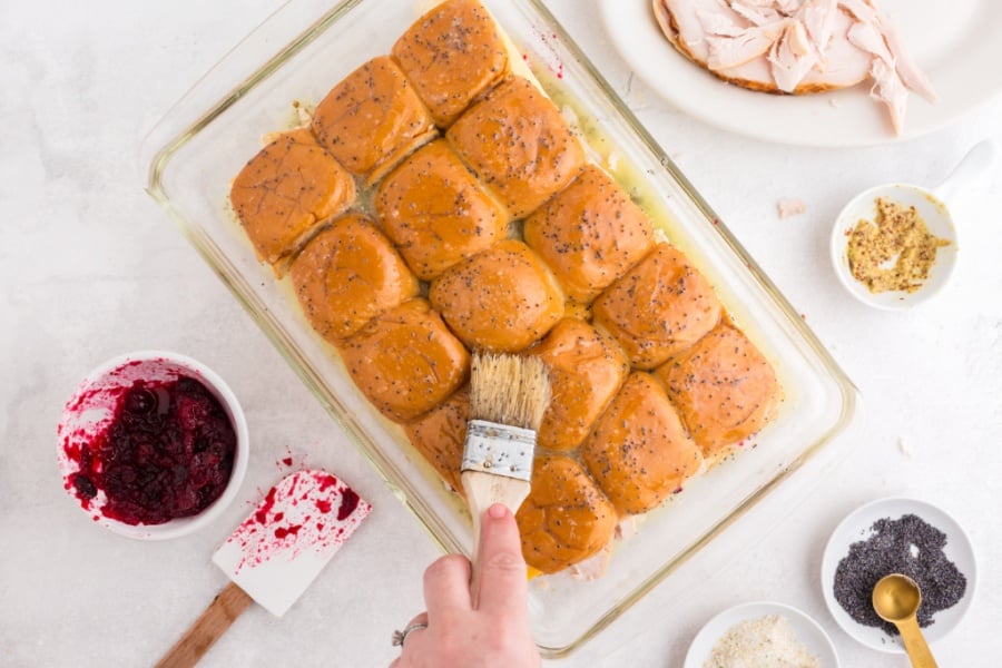 brushing butter mixture on top of buns