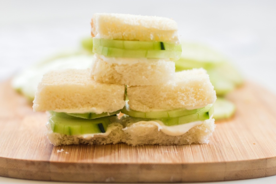 Mini cucumber sandwiches stacked on a cutting board