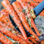 spatula scooping up some roasted carrots off of a baking sheet