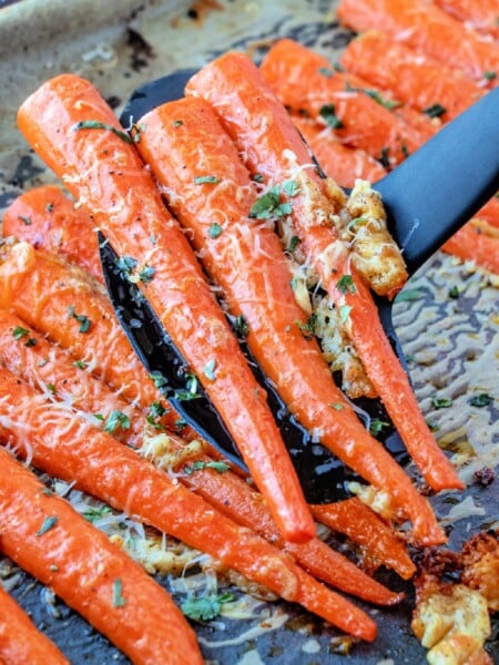spatula scooping up some roasted carrots off of a baking sheet