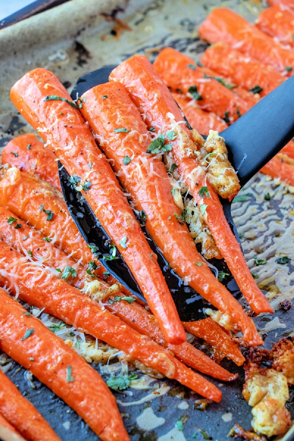 spatula scooping up some roasted carrots off of a baking sheet