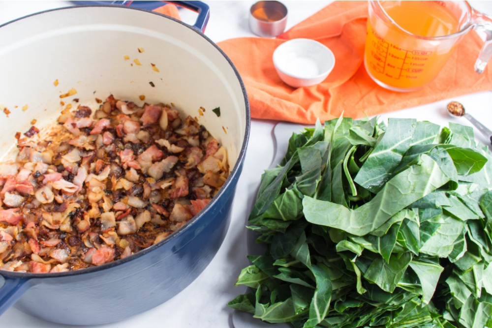 cooked bacon and onion in cooking pot and a pile on greens