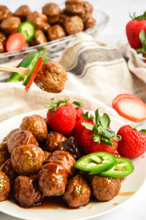 Strawberry Jalapeno Meatballs on a plate with a toothpick picking up one