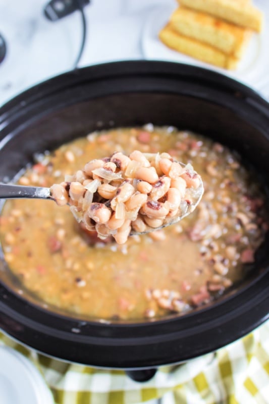 a spoon scooping up black eye peas from a crockpot