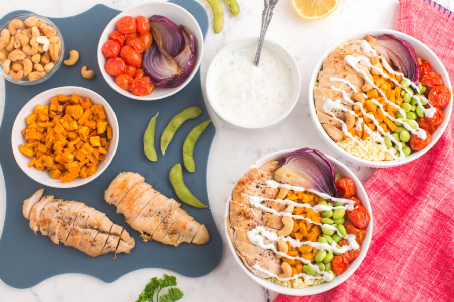 two buddah bowls with white sauce drizzle and ingredients on the site