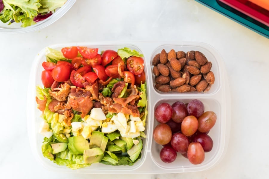 top down picture of lunchbox packed with cobb salad, grapes and almonds