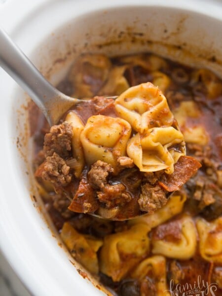 serving spoon scooping up pizza soup from slow coker