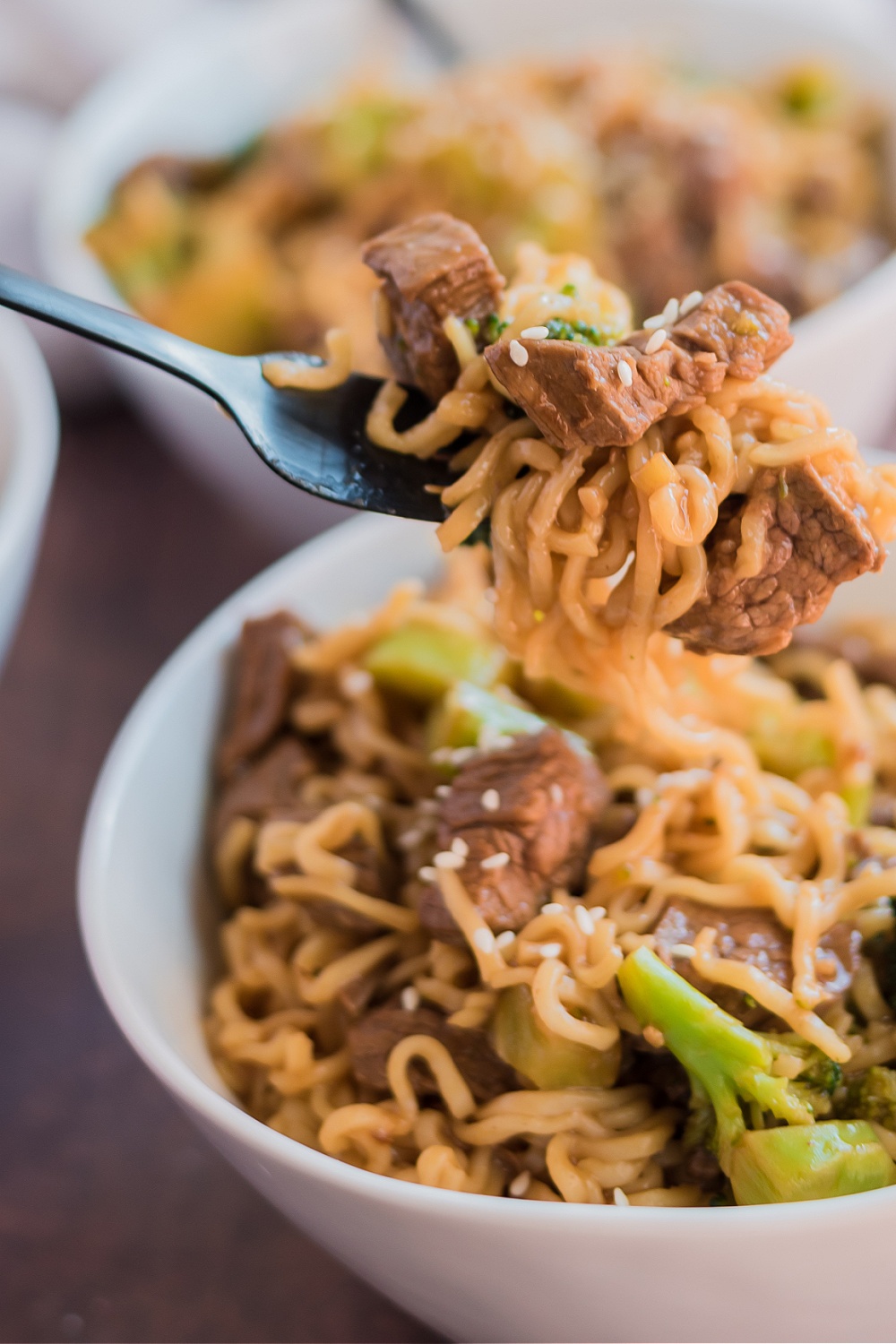 Take-Out Beef and Broccoli Ramen Noodles in two bowls with a fork picking up some