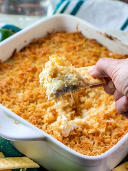 hand scooping up some jalapeno dip with a cracker