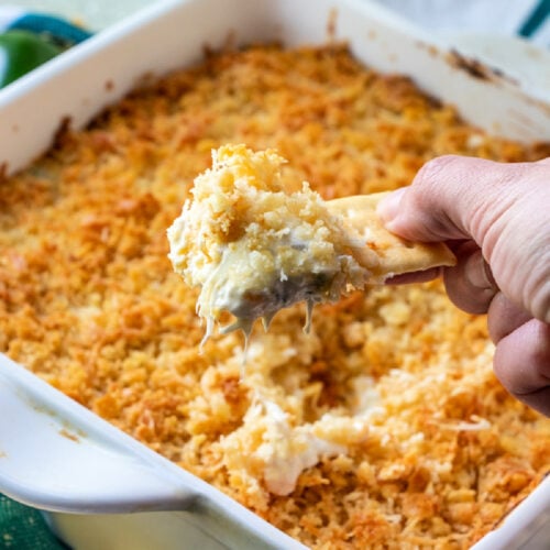 hand scooping up some jalapeno dip with a cracker