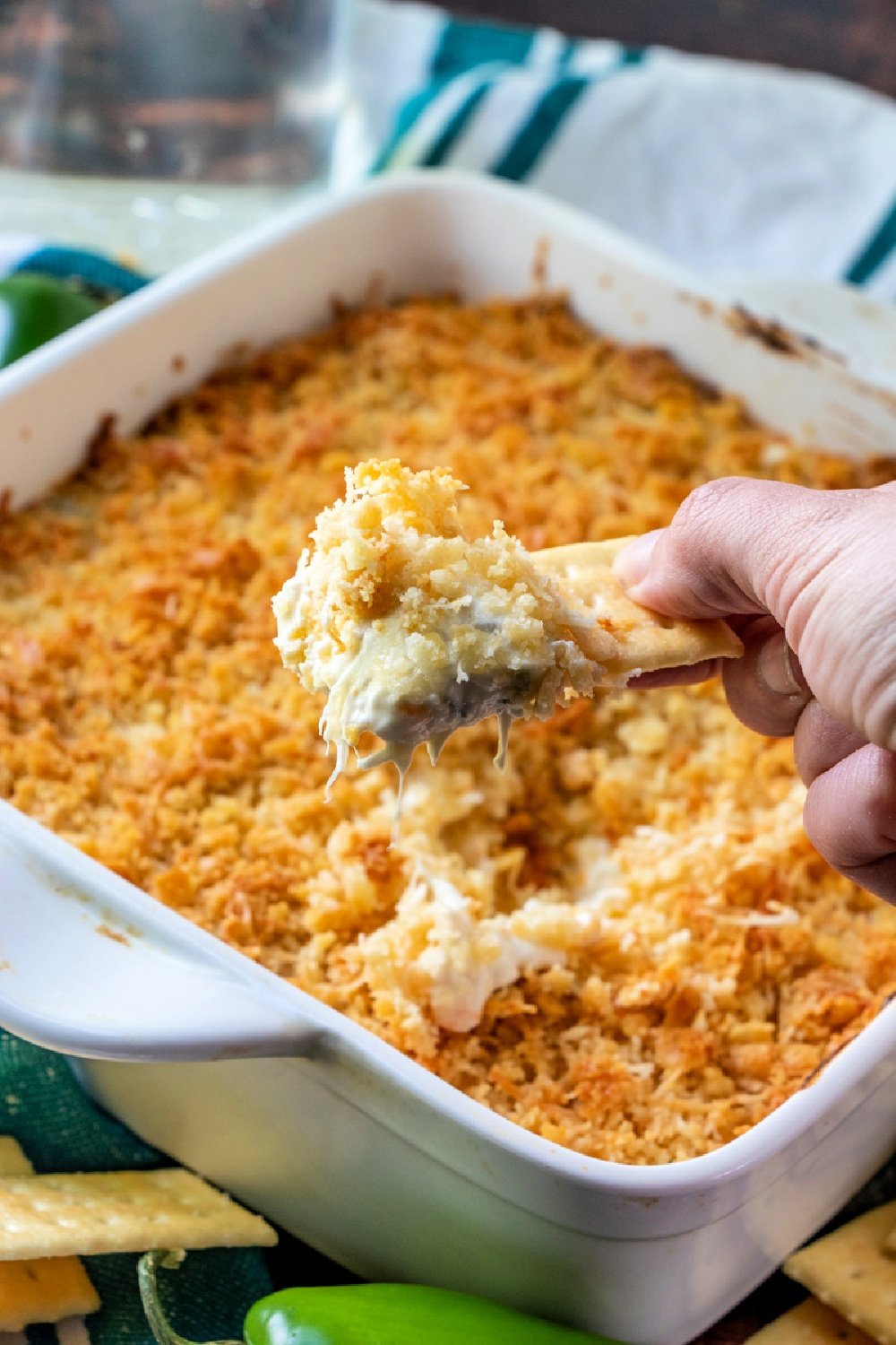 hand scooping up some jalapeno dip with a cracker