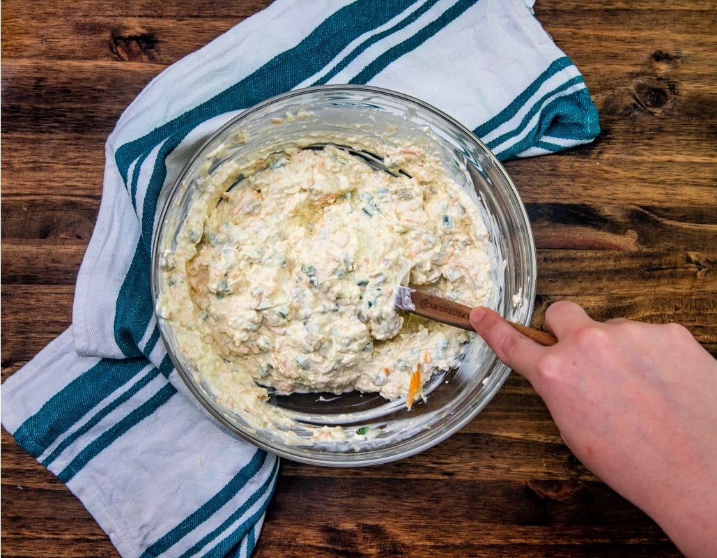 cream cheese, mayonnaise, green chili & jalapeno peppers, cheddar cheese and Monterey Jack cheese being mixed in a mixing bowl