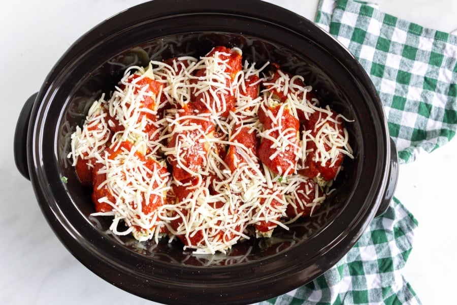 stuffed shells in slow cooker topped with red sauce and shredded cheese