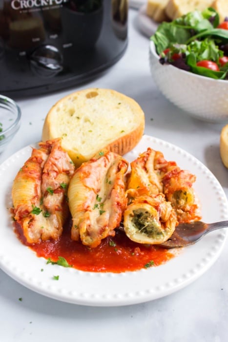 3 stuffed shells on a plate with a piece of bread