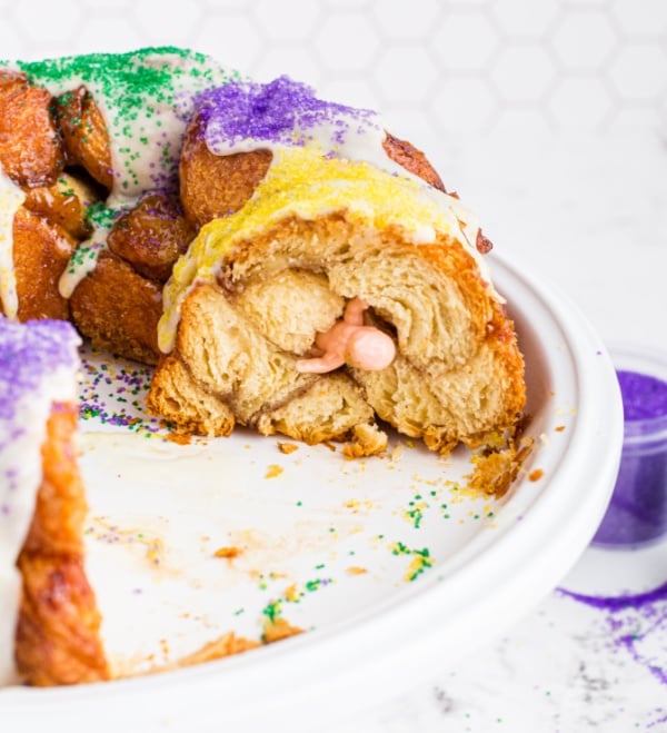 a piece of king cake cut out and a plastic baby in the cake