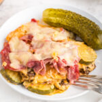 piece of reuben casserole on a plate with a pickle