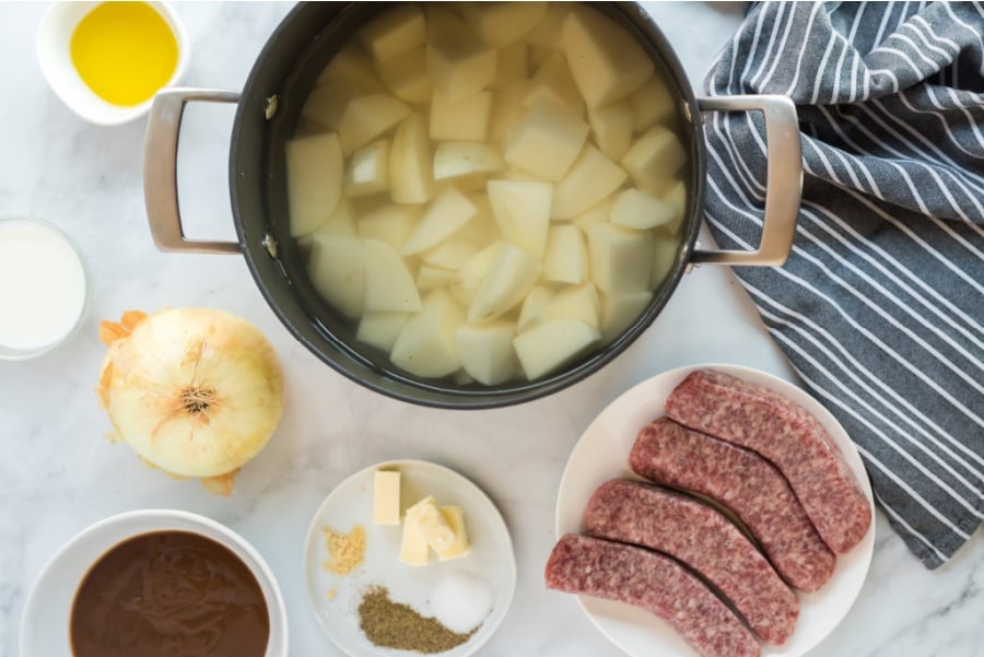 potatoes in a bot of water and sausages on a plate