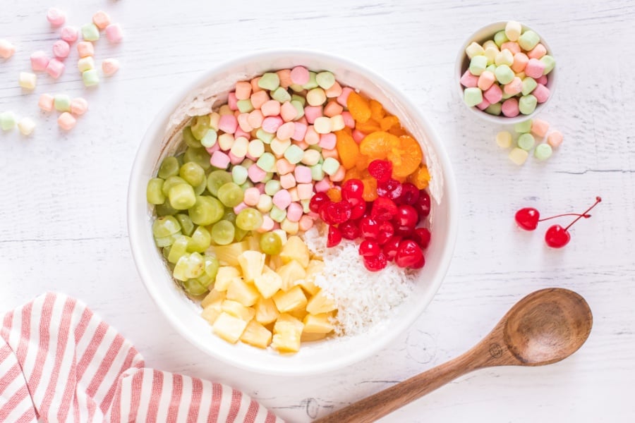 Marshmallows, pineapple, mandarin oranges, cherries, grapes, and coconut added to mixing bowl