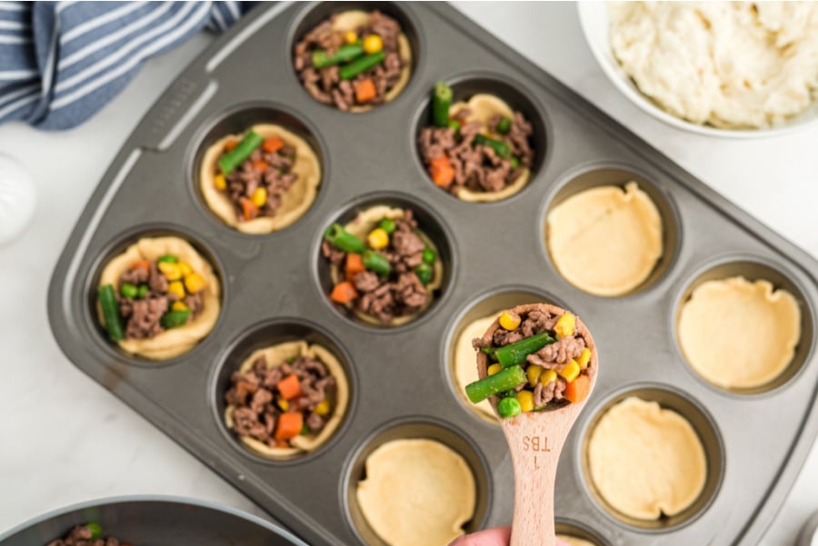 scooping beef mixture into muffin tin