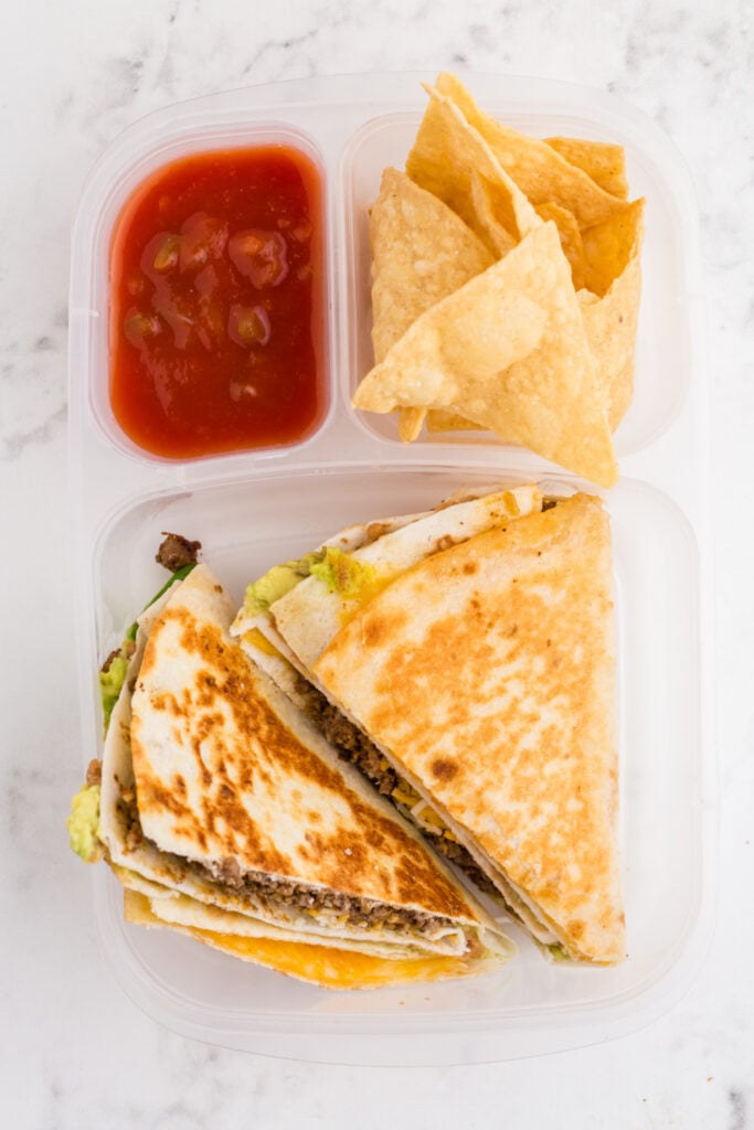 quesadillas packed in a lunchbox container with salsa and chips