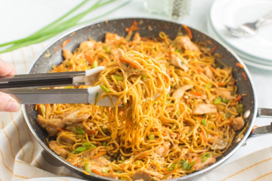 Chicken Chow Mein in a pan with tongs pick up some