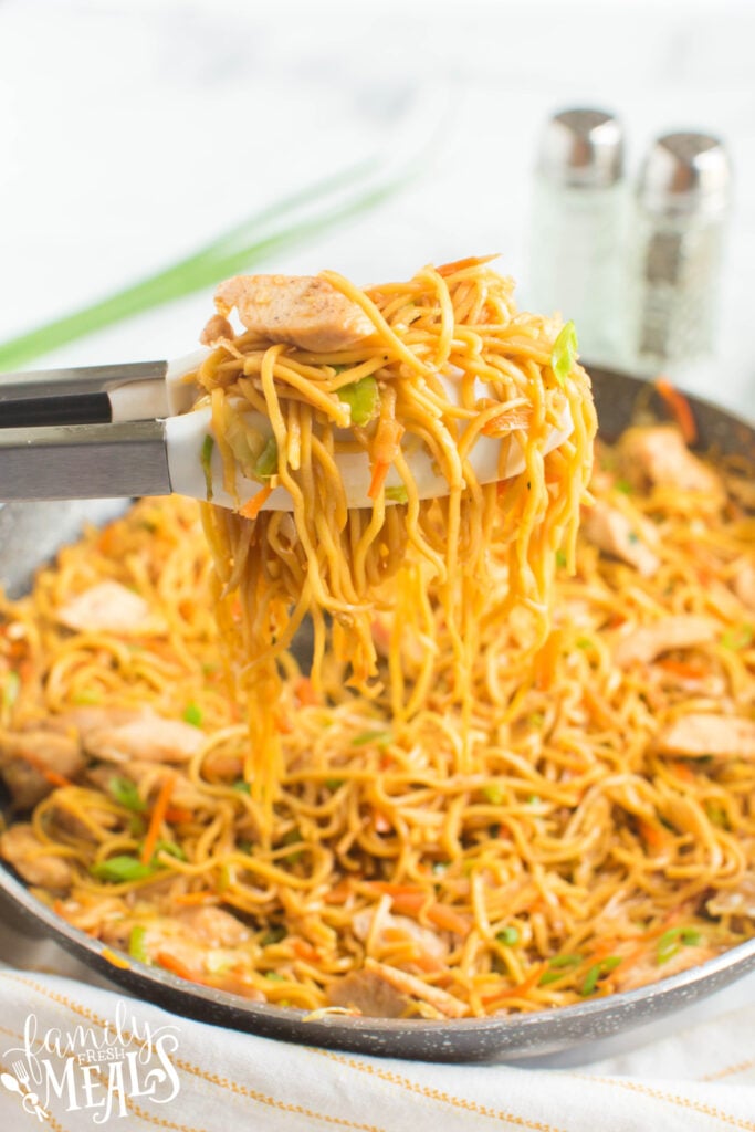 Chicken Chow Mein in a pan with tongs pick up some