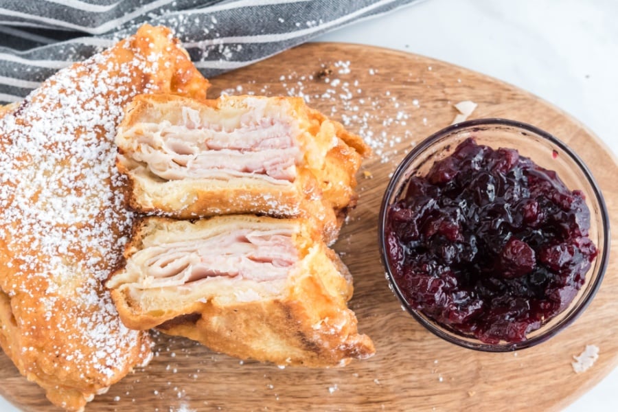 Monte Cristo sandwich on a cutting board with a bowl of jam