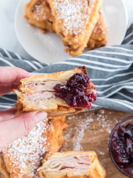 hand holding a monte cristo sandwich dipped in jam