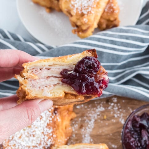 hand holding a monte cristo sandwich dipped in jam