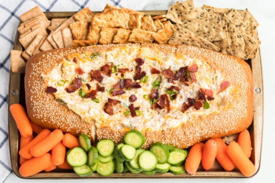 Mississippi Sin Dip in a bread loaf, surrounded by veggies and crackers 