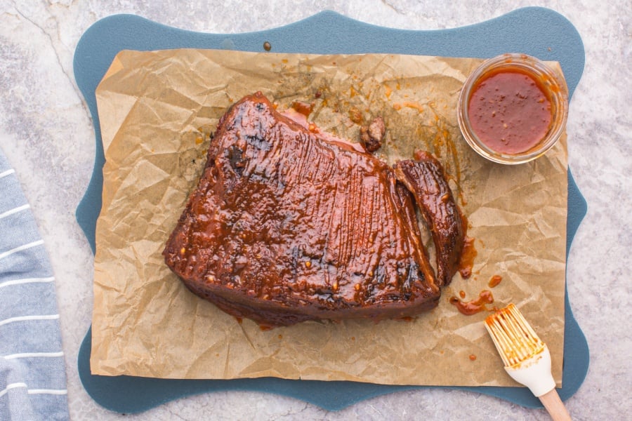  BBQ Brisket on parchment paper with a small up of bbq sauce