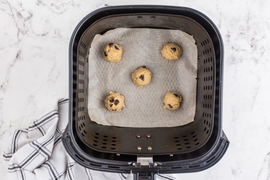 5 cookie dough balls in an air fryer basket