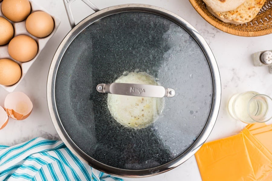 egg cooking in pan with lid on