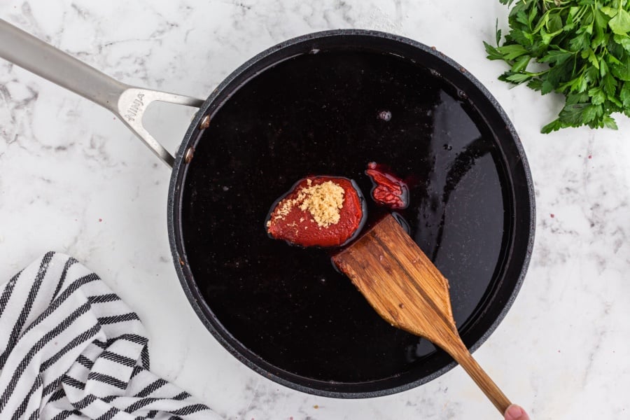 adding beef broth, tomato paste, and brown sugar to the skillet