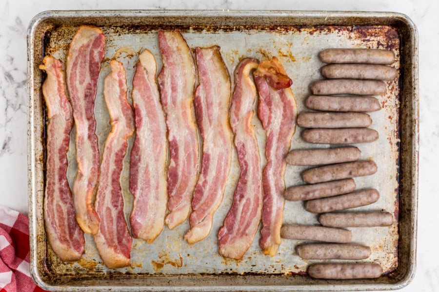 cooked bacon and cooked sausage on baking sheet