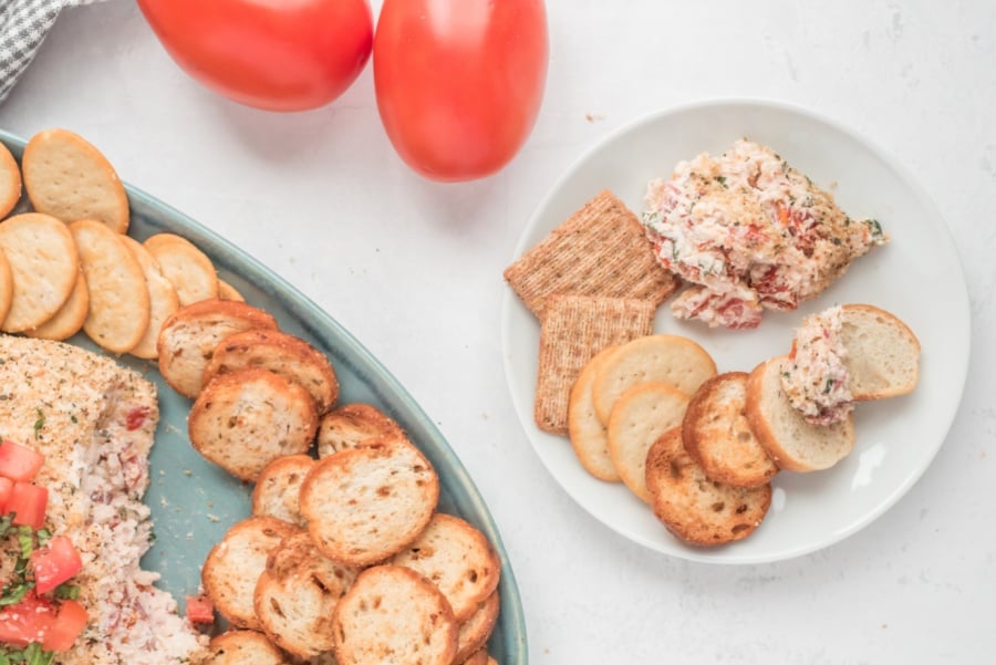 a scoop of Bruschetta Cheese Ball on a plate with crackers