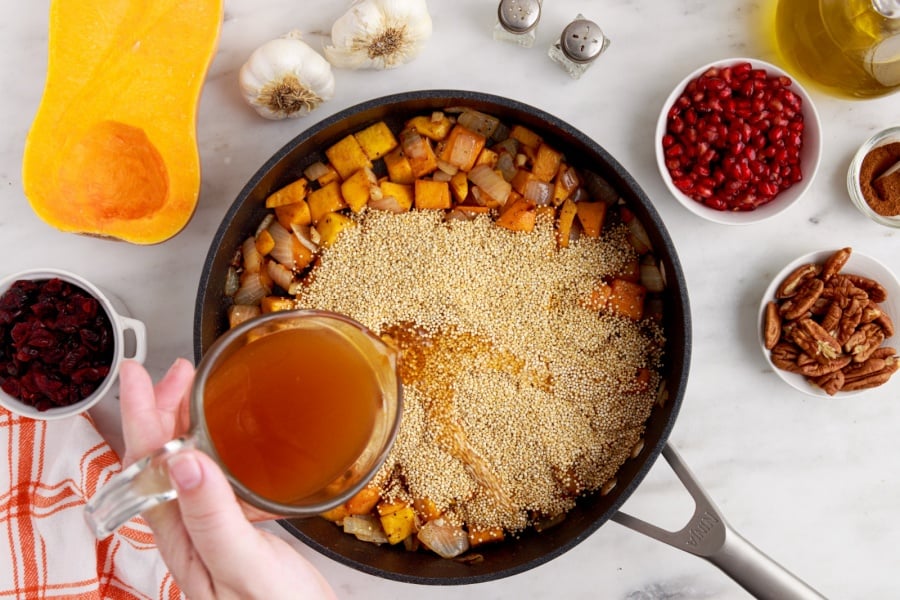 adding broth and quinoa into pan