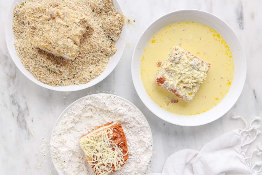 show lasagna pieces in flour, egg and bread crumb mixtures