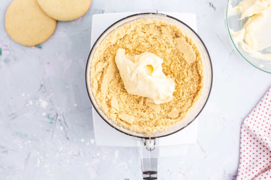 adding cream cheese mixture to cookie crumbs