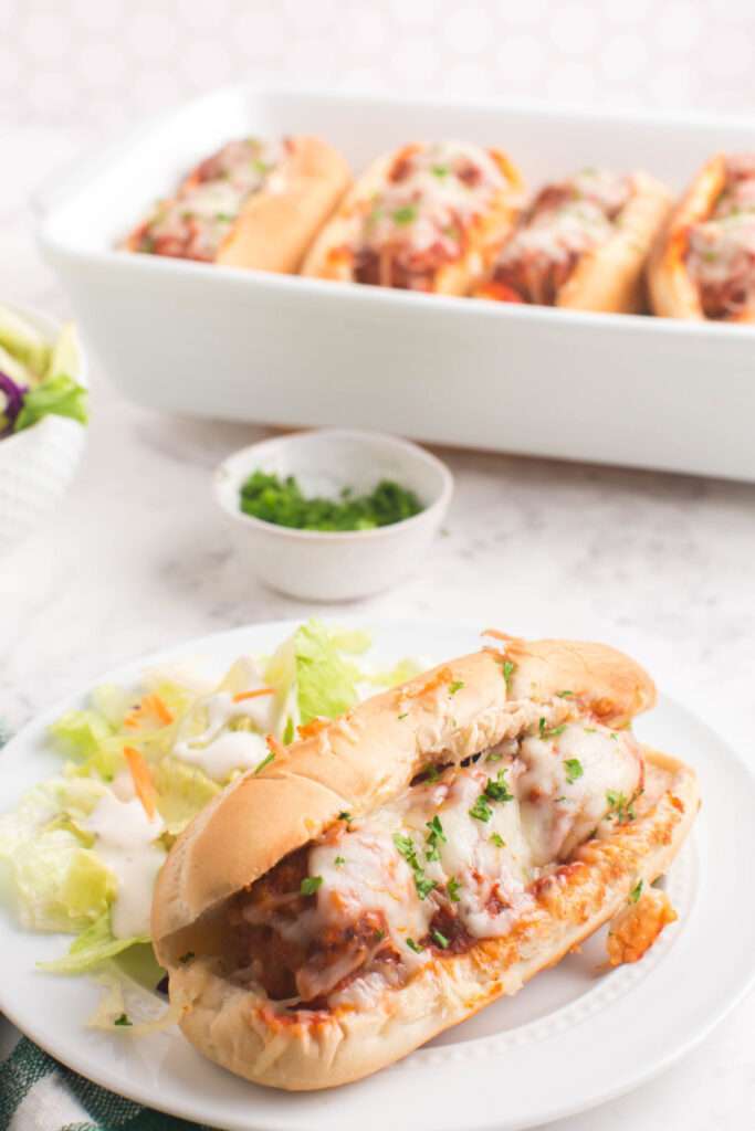 Baked Meatball Sub on a plate with a salad