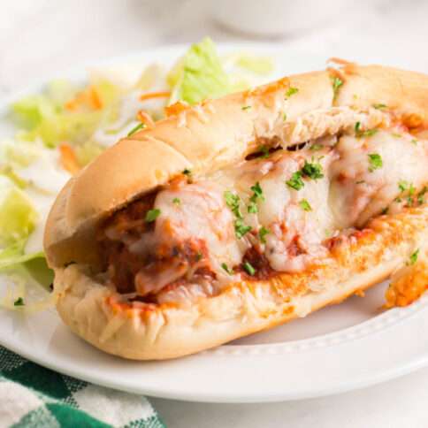 Baked Meatball Sub on a plate with a salad